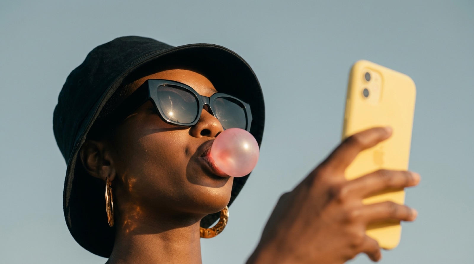 Someone blowing a bubblegum bubble while checking their phone